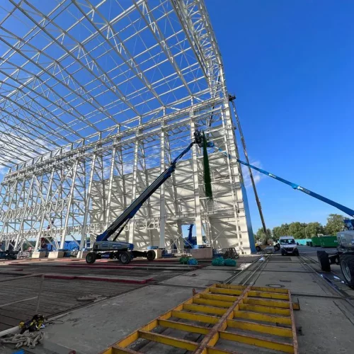 Arbeiter in Kran montiert Netz an Werftgerüst